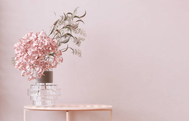 Pastel pink side table podium, hydrangea flower bouquet in modern design glass vase in sunlight on wallpaper wall