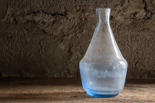 An old bottle made of blue glass. An old dusty bottle on a stone background.