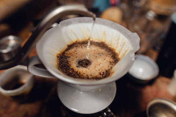 istock Man pouring hot water on ground coffee with paper filter to making a drip coffee 1465757991