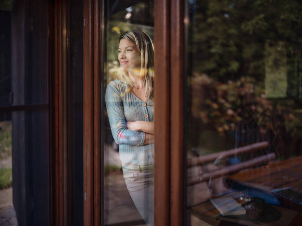 istock Smiling woman looking through window from her home. 1465762502