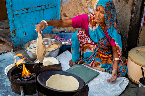 Indian street vendor preparing food - chapatti, flat bread, in The Pink City of Jaipur, Rajasthan, India.  Jaipur is known as the Pink City, because of the color of the stone exclusively used for the construction of all the structures.