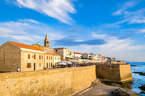 Tourists strolling along the Bastioni di Marco Polo in Alghero, the ramparts that are part of the 13th-century defense system and that still today surround the old town