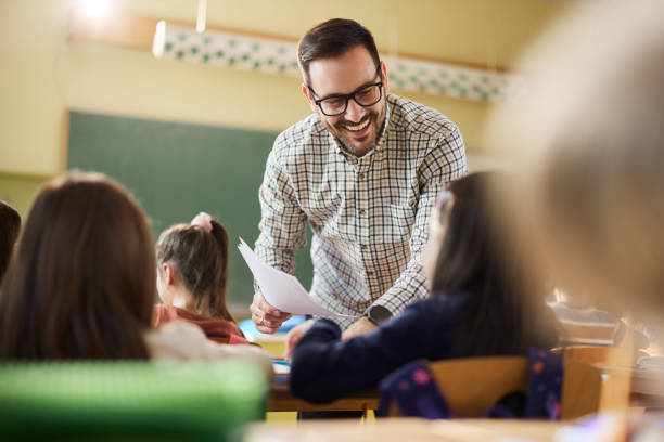 istock Happy professor assisting schoolgirl on a class at school. 1465763947