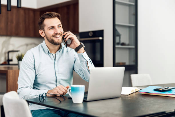 istock Young freelancer is smiling, typing on his laptop in nice modern home 1465767343