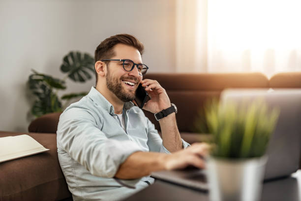istock Young freelancer is smiling, typing on his laptop in nice modern home 1465768094