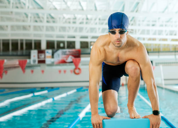 A young swimmer ready to jump on the diving board at the start of the pool stock photo