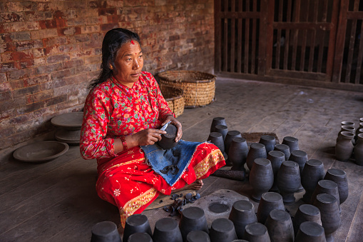 Nepalese woman working on pottery square in Bhaktapur. Bhaktapur is an ancient town in the Kathmandu Valley and is listed as a World Heritage Site by UNESCO for its rich culture, temples, and wood, metal and stone artwork.