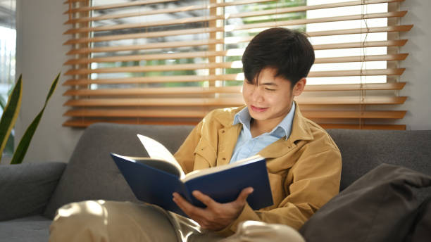 istock Satisfied man reading book, relaxing on comfortable couch at home. Leisure activity, positive mood concept. 1465786159