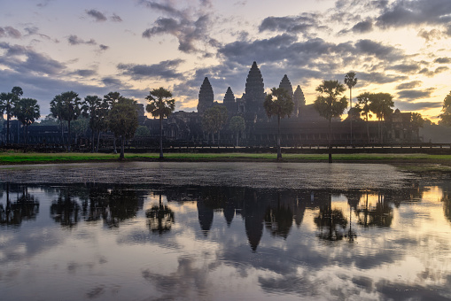 Majestic Angkor Wat Temple backlit from sunrise light under beautiful cloudy sky, reflecting in Angkor Wat Pond. Angkor Wat, Siem Reap, Cambodia, Southeast Asia.