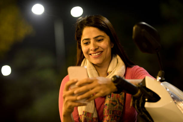 istock Happy woman chatting on mobile phone while sitting on motorcycle at night 1465787559