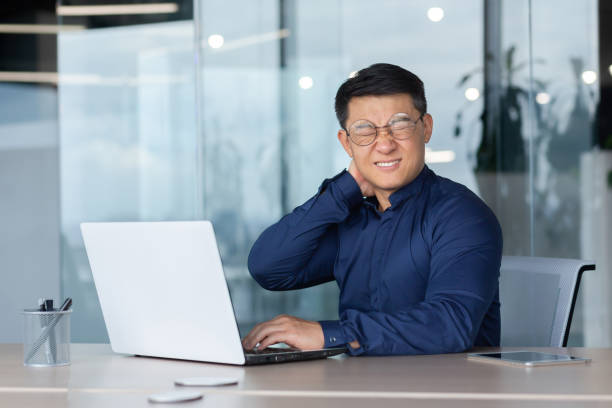 istock Overtired office worker at work with laptop inside office, man has severe neck pain, Asian man works long time sitting. 1465787762