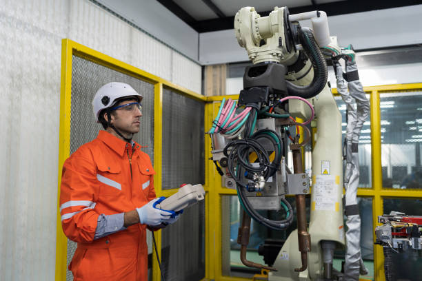 istock Male engineer repair or maintenance automatic robot arm system in the manufacturing automation and robotics academy room. Male technician working with robotic arm system. Robot maintenance concept 1465789645