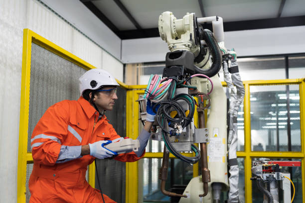 istock Male engineer repair or maintenance automatic robot arm system in the manufacturing automation and robotics academy room. Male technician working with robotic arm system. Robot maintenance concept 1465789658