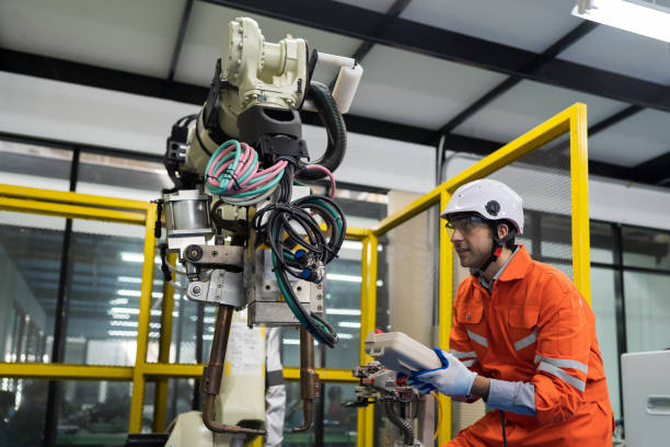 istock Male engineer repair or maintenance automatic robot arm system in the manufacturing automation and robotics academy room. Male technician working with robotic arm system. Robot maintenance concept 1465789664