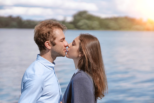 couple in love kissing standing on the shore of the lake . side view.