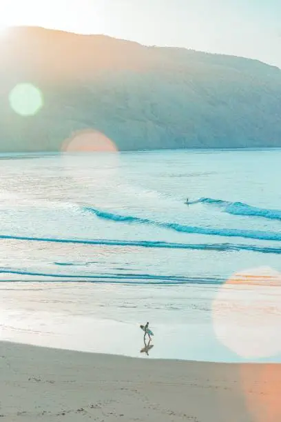 Photo of Male surfer on the sandy beach on a windy day