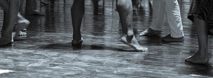 A grayscale shot of the feet of dancers practising in the studio