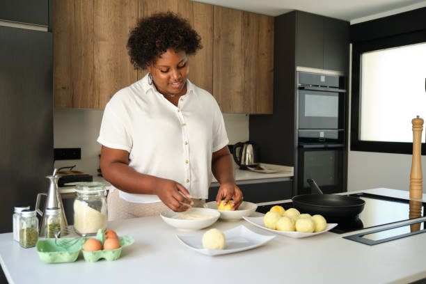 istock Young cuban woman breading mashed potatoes balls. 1465798314