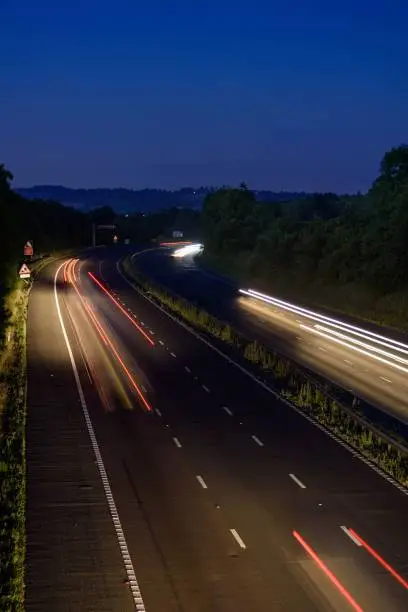The fast moving cars on the M5 highway leave traffic light trails and light streaks as they pass along a busy motorway