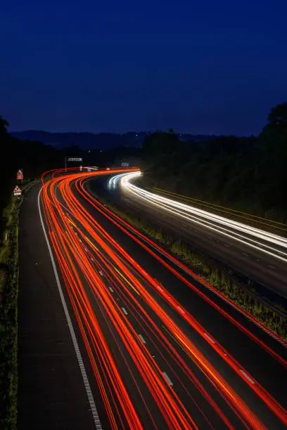 The fast moving cars on the M5 highway leave traffic light trails and light streaks as they pass along a busy motorway