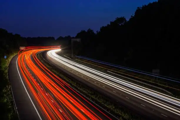 The fast moving cars on the M5 highway leave traffic light trails and light streaks as they pass along a busy motorway