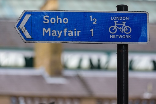 A street sign in London directs cyclists towards Mayfair and Soho along the London Network for cycles and bikes.