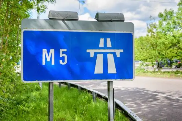 A blue street sign informs drivers the road they are driving on is the M5 motorway.