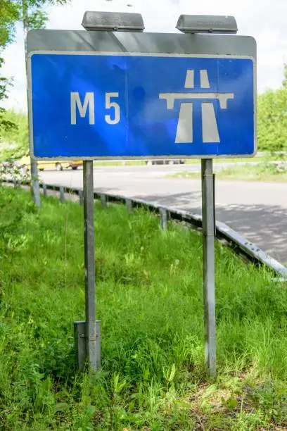 A blue street sign informs drivers the road they are driving on is the M5 motorway.