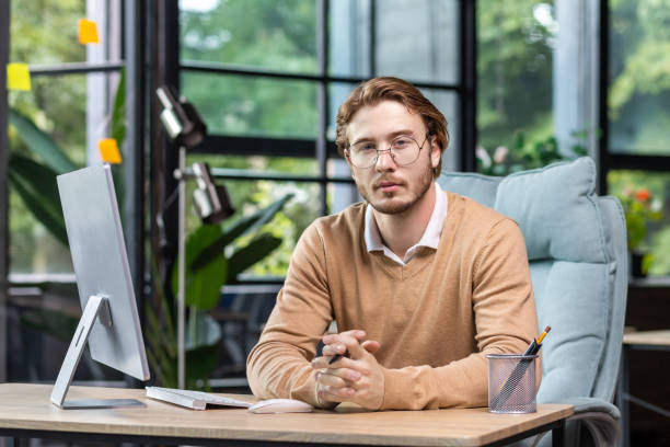 istock Portrait of thinking serious man with computer inside modern green loft office, blond man looking thoughtfully at camera businessman in casual clothes working with computer 1465802707