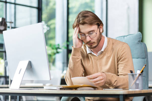 istock Man upset in office reading message on paper, businessman received mail envelope with notification and bad news, sitting at workplace with computer 1465802846