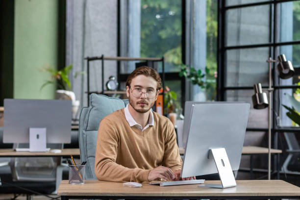 istock Portrait of thinking serious man with computer inside modern green loft office, blond man looking thoughtfully at camera businessman in casual clothes working with computer 1465802919