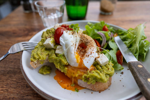 istock Sourdough toast, poached eggs, avocado pulp and fresh vegetables on plate in cafe, close up 1465817596