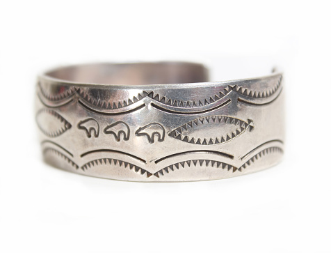 A closeup shot of a vintage silver handmade bracelet from the Southwest on a white background