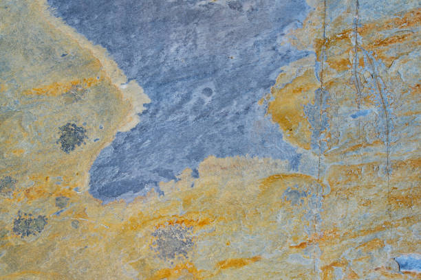 Rough stone texture with rust in blue and yellow colors with orange placed on a wall on a facade