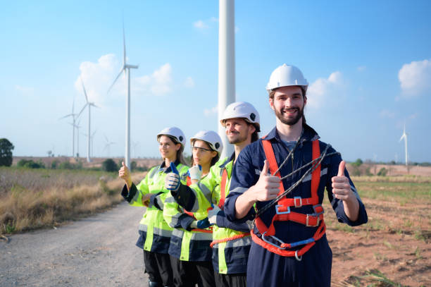 retrato del ingeniero estacionado en el sitio de natural energy wind turbine. con tareas diarias de auditoría de las principales operaciones de aerogeneradores que transforman la energía eólica en electricidad eléctrica - alternative energy electricity wind turbine team fotografías e imágenes de stock