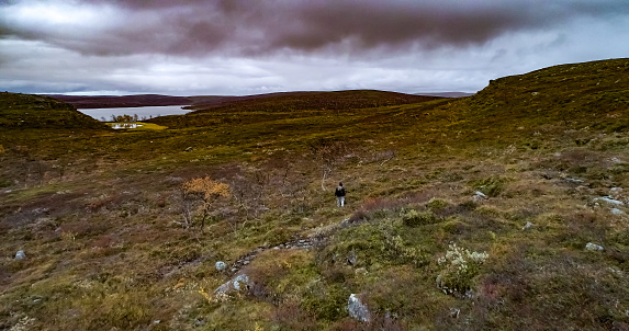 Aerial drone view of a man lost, walking in polar wilderness, rainy, autumn day, in Finnmark, Norway