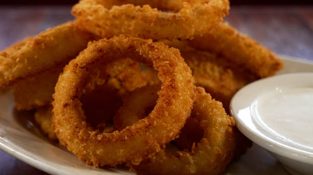 istock Selective closeup of fried onion rings on a white plate 1465831426
