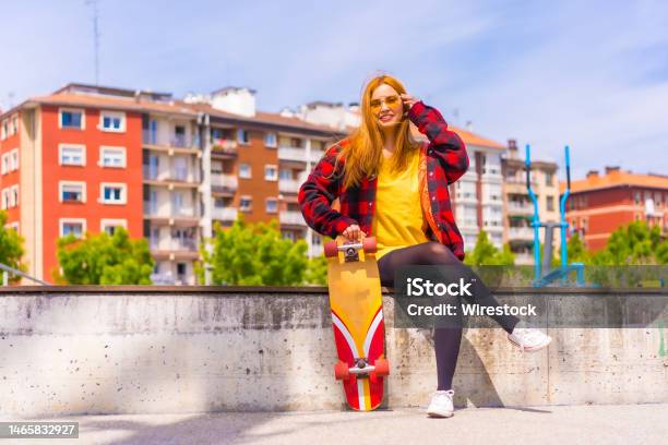 Stylish Redhead Hispanic Lady Enjoying A Sunny Day In An Urban Park Holding Her Skateboard Stock Photo - Download Image Now
