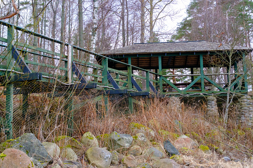 Wooden canopy, sitting area in green. Wooden walkway with railings.