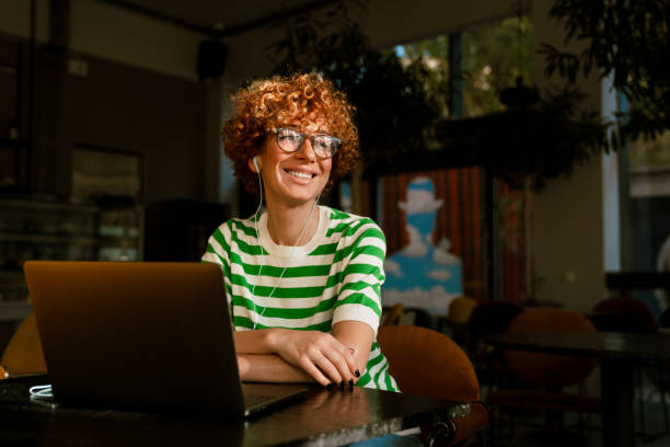 istock Mid white woman with curly hair using laptop while sitting in cafe 1465854912