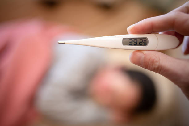 istock A sick child and a parent's hand with a thermometer 1465855659