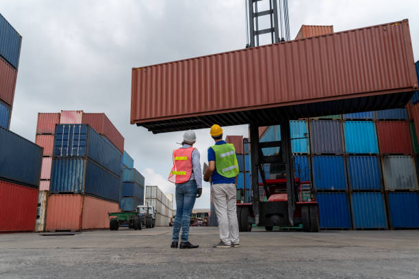 istock Industrial worker works with co-worker at overseas shipping container yard . Logistics supply chain management and international goods export concept . 1465856994
