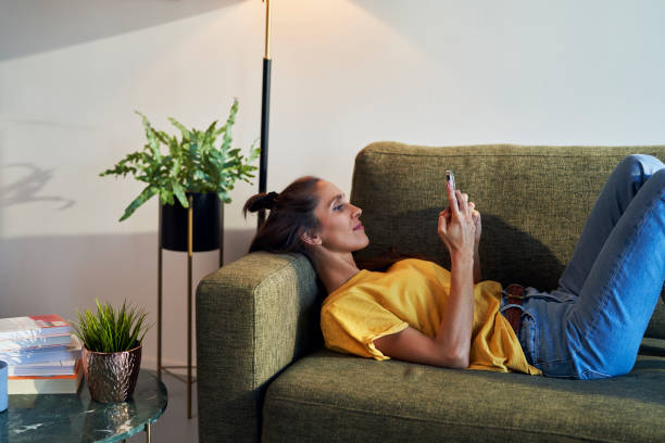 istock Caucasian woman lying on sofa and browsing phone 1465858996