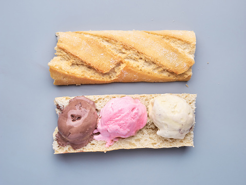 a baguette slice filled with three different flavored ice cream scoops, with copy space