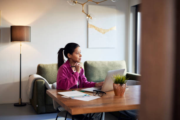 istock Woman in purple jacket working on computer at home 1465860403