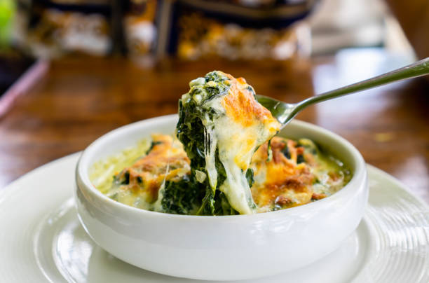 Spoon scoop up baked Spinach with Cheese in white bowl. Spoon scoop up baked Spinach with Cheese in white bowl. spinach pasta stock pictures, royalty-free photos & images