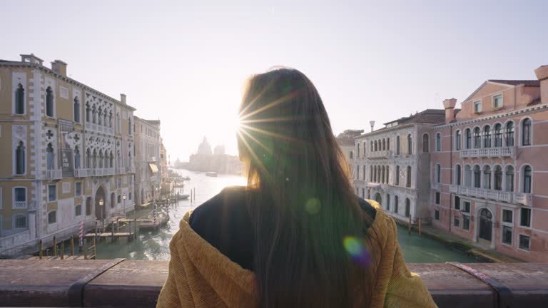 Silhouette sunset of woman standing on the bridge in Venice.