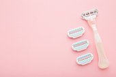 New razor with change heads on light pink table background. Pastel color. Closeup. Female product for smooth body skin. Empty place for text. Top down view.