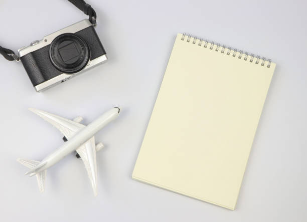 istock flat lay of blank page opened notebook, airplane model  and camera on white  background with copy space. Travel, photo and memory concept. 1465868057