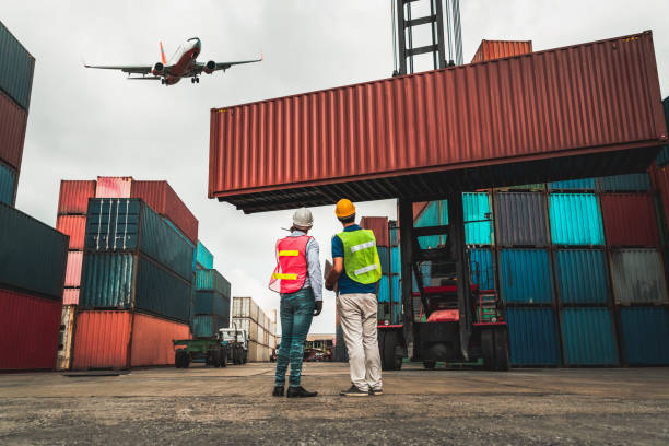 istock Industrial worker works with co-worker at overseas shipping container port . Logistics supply chain management and international goods export concept . 1465871665